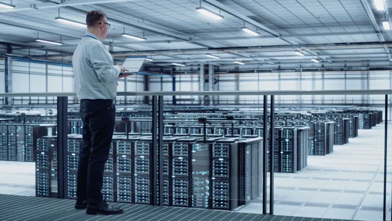 ingeniero de centro de datos que utiliza una computadora portátil. facilidad especializada en computación en la nube de la granja de servidores con administrador de sistemas masculino adulto que trabaja con la red de protección de datos para la seguridad cibernética.