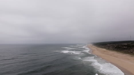 misty beach coastline with wind farm