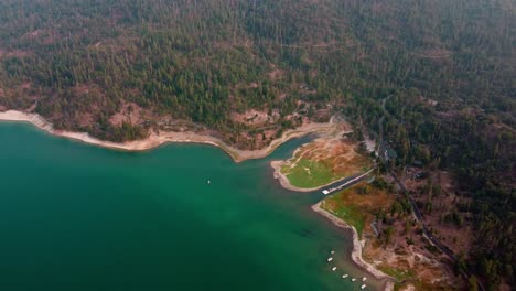 aerial drone flyover lake shore waters and forested foothills surrounding bass lake, california