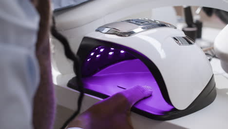 person getting their nails cured in a uv lamp at a nail salon.