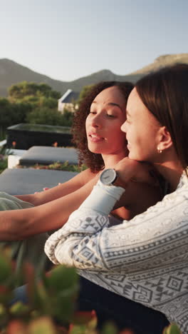 vertical video of happy biracial female couple admiring view in garden in slow motion