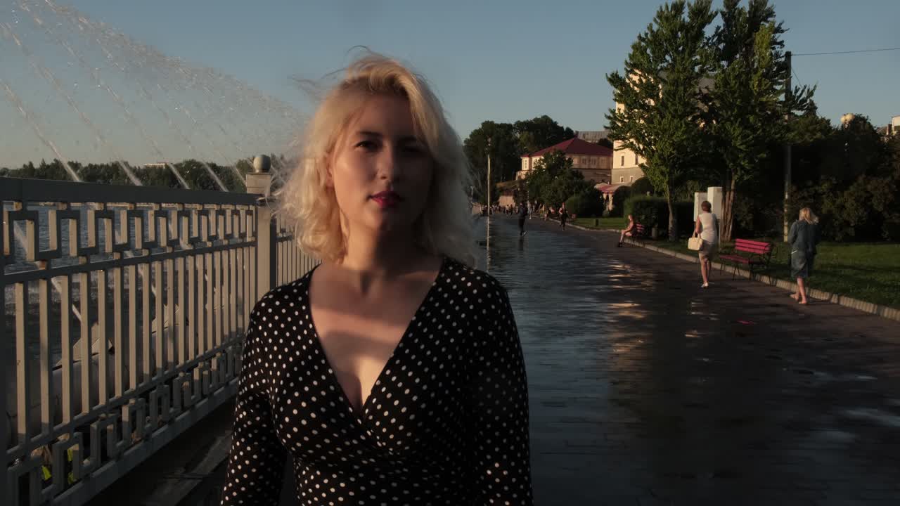 сексуальная блондинка прогуливается по улице у озера