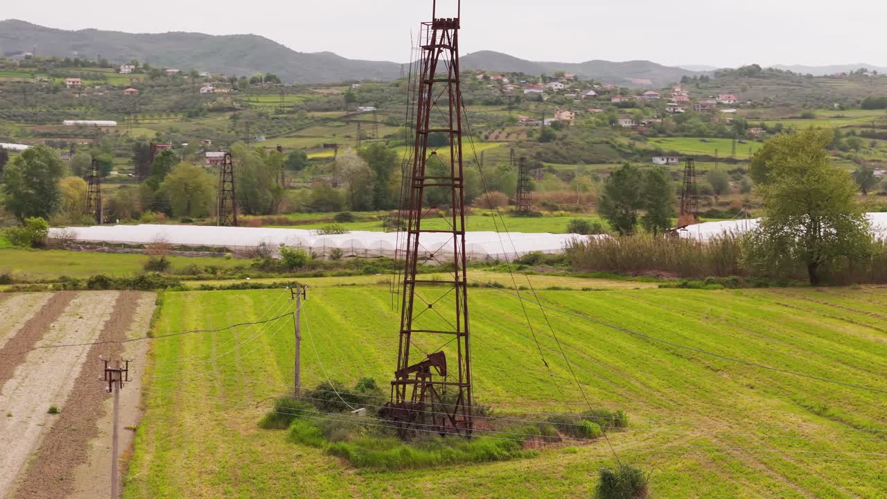 Quiet Albanian oil field view with greenery and distant hills in Kucova