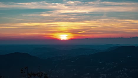 Dramatic-sunset-sky-of-magenta-and-red-in-thin-clouds-over-mountains-fades-to-teal-and-blue-in-time-lapse