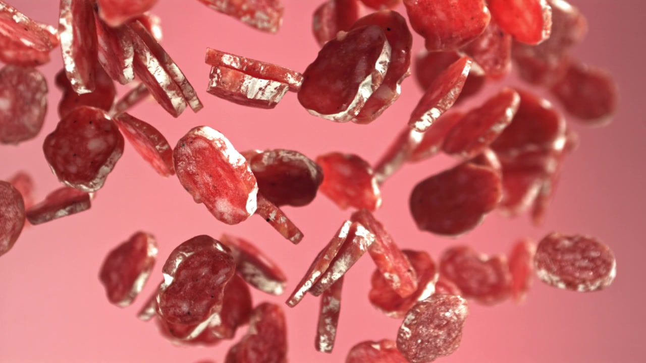 Salami Slices Falling in Slow Motion on Pink Background