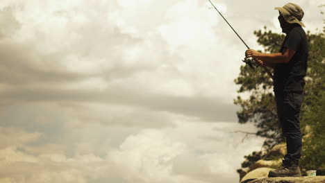 Fisherman-standing-on-the-rock-casting-the-bait-in-to-the-lake