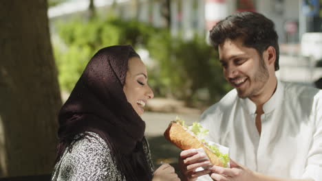 Young-muslim-couple-having-fun-while-eating-lunch-in-park.