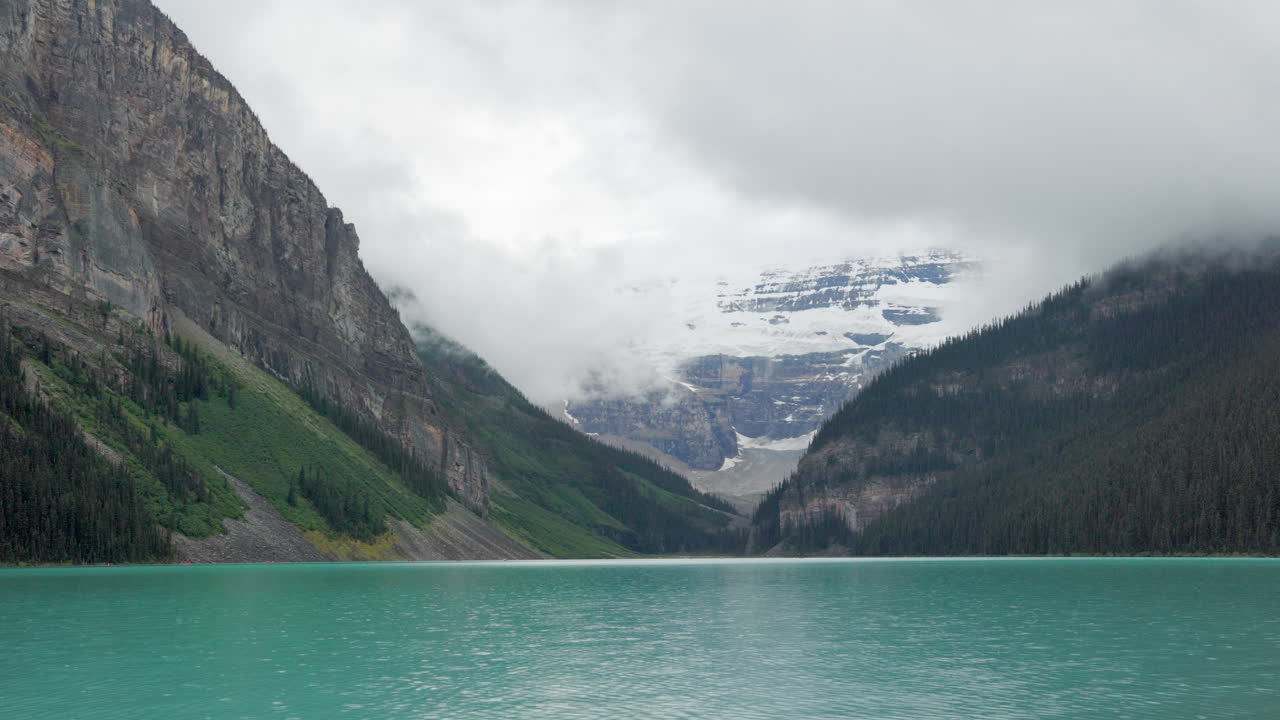 Rainy day at Lake Louise in the Canadian Rockies, with mist-covered peaks and tranquil turquoise water