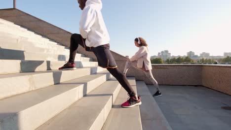 pareja joven estirando las piernas en las escaleras al aire libre