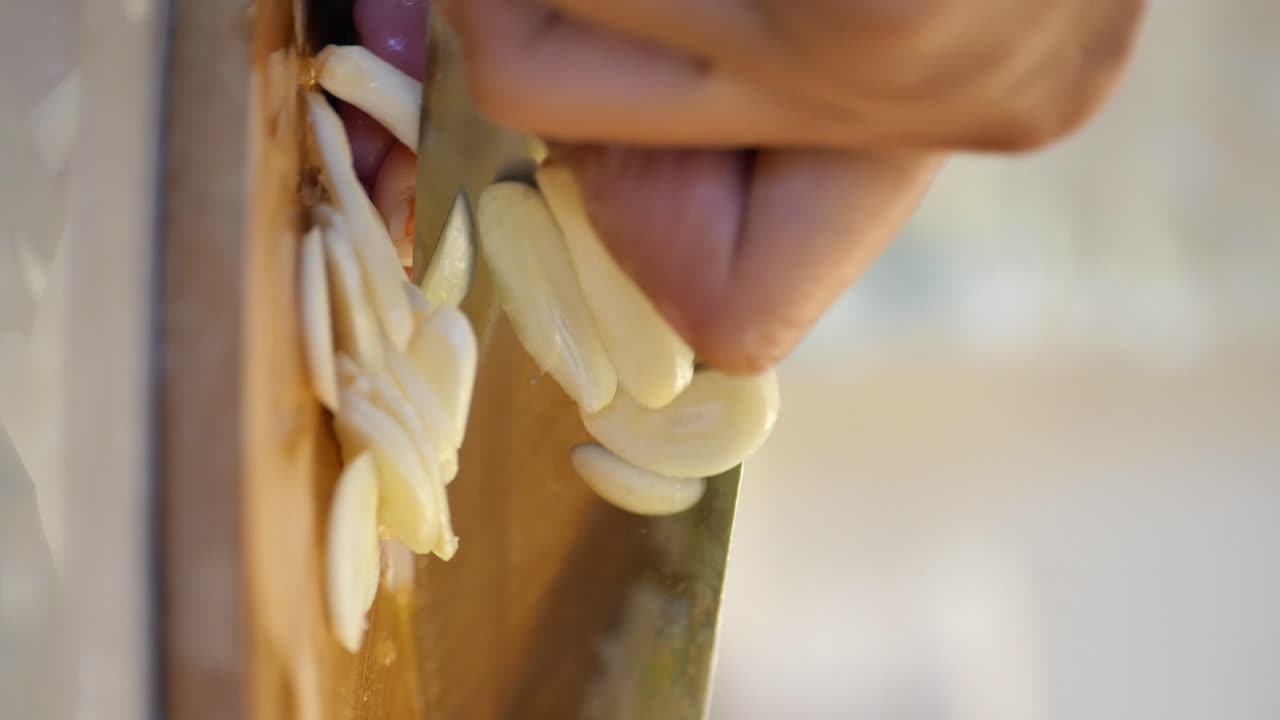 Slicing garlic with a knife on a wooden board