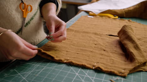 fashion designer seamstress pinning together fabric cut from a sewing pattern template