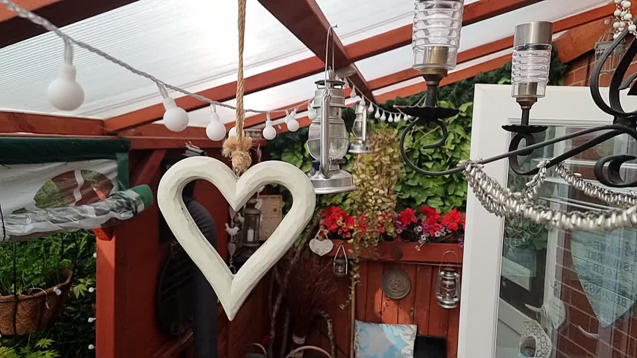 평화로운 고립 된 야외 정원 성소 내에 매달려있는 시골 나무 심장과 요정 빛