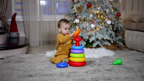 baby playing with stacking rings by christmas tree