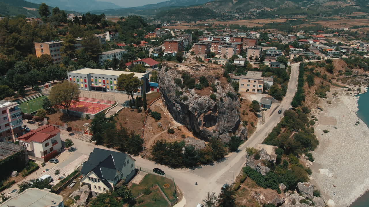 Ohromující letecký pohled ukazující panorama města Permet v Albánii. Kamera obíhá kolem výrazné velké skály poblíž řeky Vjosa.