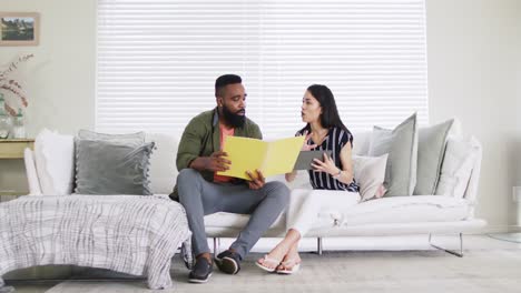 Diverse-female-and-male-friends-in-discussion,-holding-files,-working-at-home,-in-slow-motion