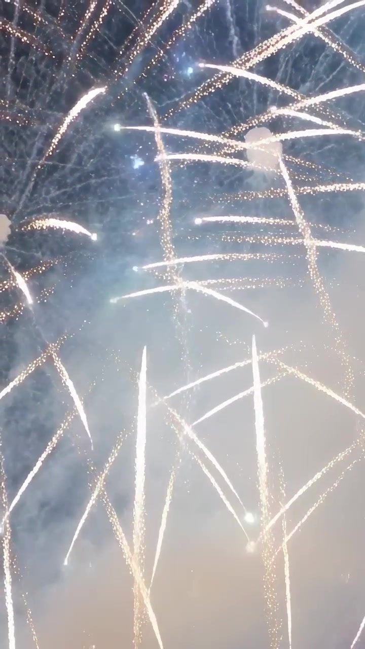 Vertikales Video: Aufsteigende Raketen erzeugen Kometenschweif-Explosionen, die den Nachthimmel für eine Show mit Rauch erhellen