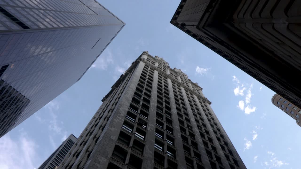 Rotating low angle perspective looking up at skyscrapers in the city on a clear sunny day