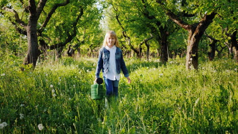 a little girl with a watering can goes on an apple orchard steadicam shot