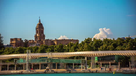 Las-Nubes-Se-Elevan-Detrás-De-La-Iglesia-Catedral-De-Málaga,-Bordeando-El-Muelle-Y-El-Paseo-Marítimo.