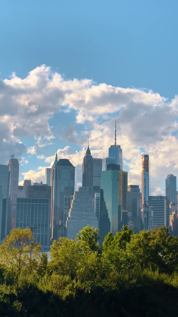 Vista do horizonte de Lower Manhattan com o One World Trade Center. Arranha-céus do distrito financeiro de Nova Iorque sob céu azul com nuvens brancas, durante o dia.