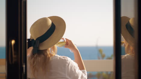 Woman-drinking-wine-and-relaxing-at-the-balcony-overlooking-sea