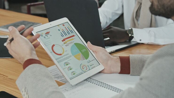 Mandlig investor analyserer virksomhedsgrafer og diagrammer på tabletskærm