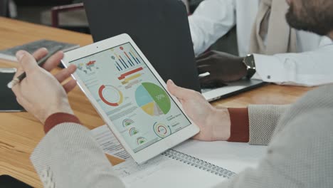 male investor analyzing business graphs and diagrams on tablet display