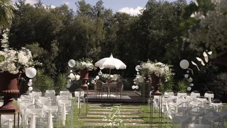 elegant outdoor wedding setup with white flowers, clear chairs, and a lakeside altar.