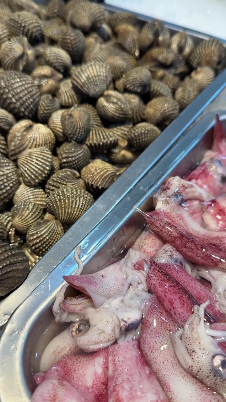 Fresh Cockles and Squid Displayed on Ice at a Seafood Market