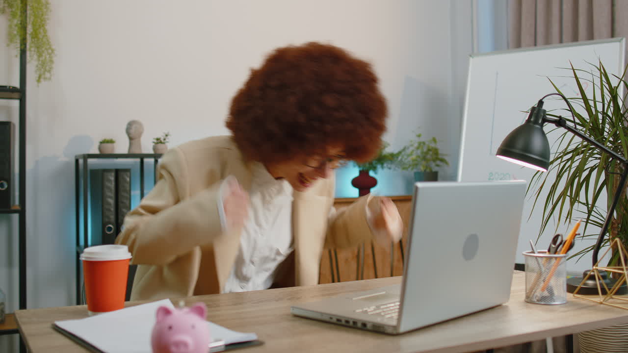 Une femme d'affaires gagnante qui travaille, navigue, tape sur son ordinateur portable au bureau, célèbre, gagne à la loterie, bonnes nouvelles.