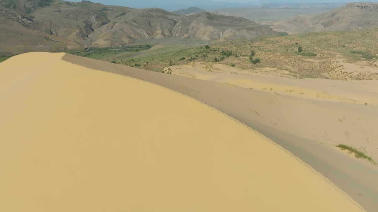 Imagens de drone da crista da duna de areia Sarykum e paisagem desértica com montanhas e vegetação esparsa perto de Makhachkala, Daguestão, Rússia, em um dia claro