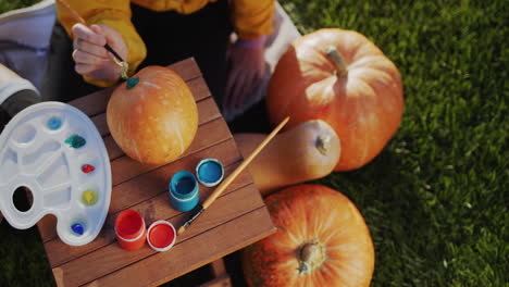 top view: a child decorates a pumpkin - prepares festive decorations