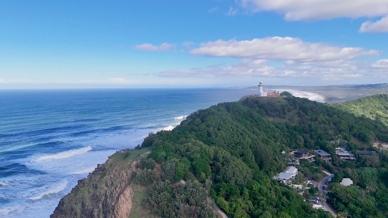 Aerial footage captures Byron Bay's lighthouse, lush forests, and coastline under clear skies, showcasing natural beauty and serene landscapes