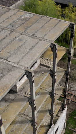 unfinished building of abandoned factory. old industrial architecture in spring. camera rising. aerial view. vertical video