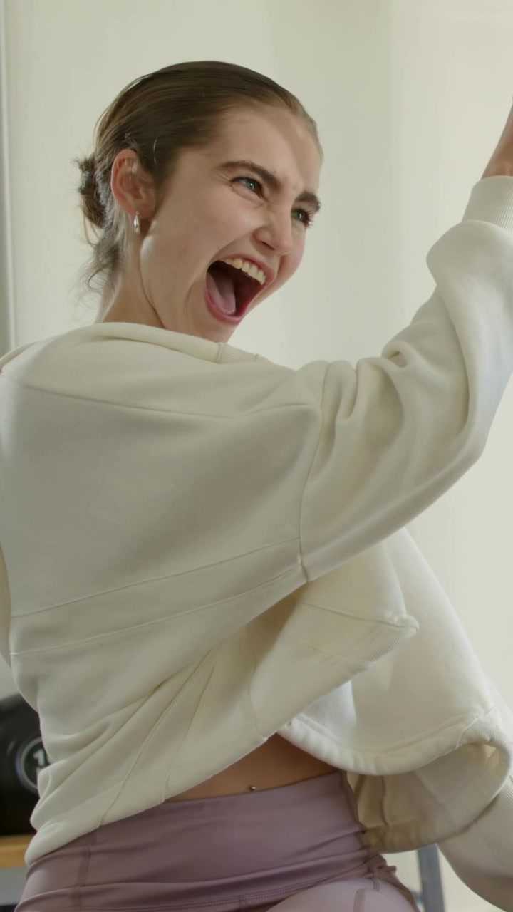 Vertical video: Turning woman in hoodie greeting at home friend entering hugging by kettlebells