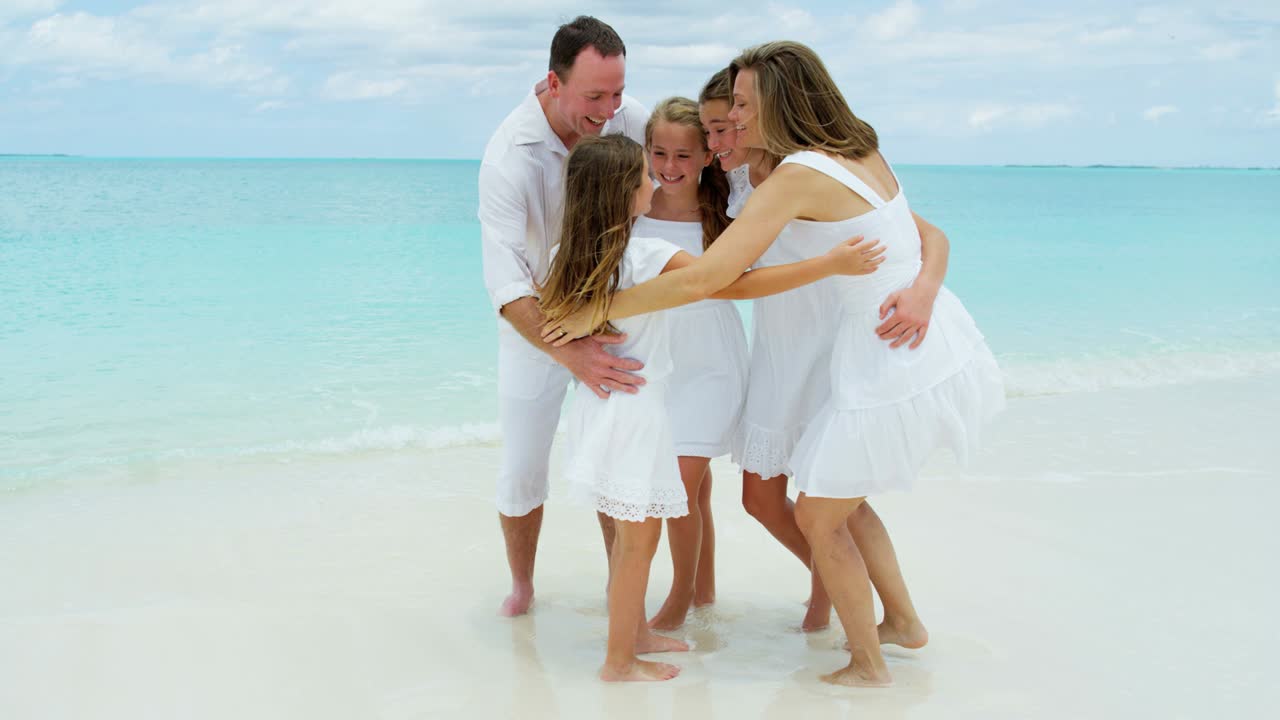 Kaukasische ouders en hun dochters genieten op het strand