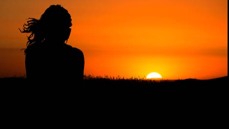 silhouette of woman looking at the sunset, mind wind blows on her hair