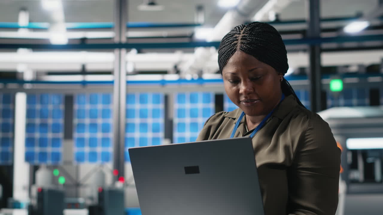 Woman working on laptop in solar panel factory