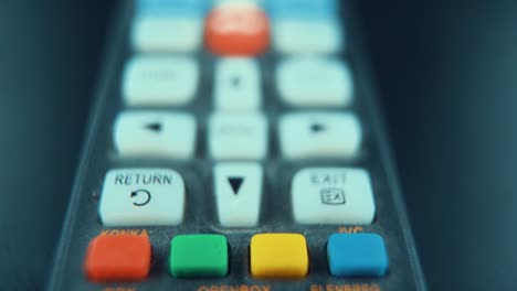A-macro-close-up-slide-shot-of-a-black-TV-remote-with-white-and-colorful-buttons,-studio-lighting,-slow-motion,-120-fps,-Full-HD
