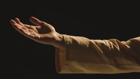 studio close up shot of man wearing robes offering helping hand