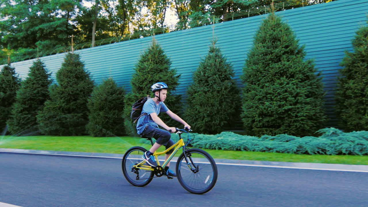 The Teenager Thirteen Rides A Bicycle Along A Green Fence