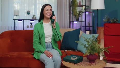 Girl-making-retro-telephone-from-90s-conversation-with-friends-sitting-call-on-couch-at-home-in-room