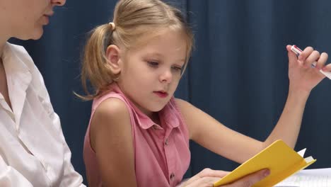 girl doing homework with her mother