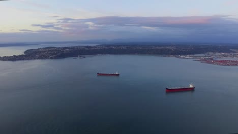 ships adrift on the dark blue sea at the commencement bay in washington, usa on a sunset - aerial shot