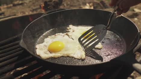 cerrar la cocina usando una espátula para separar dos huevos cocinados en la sartén