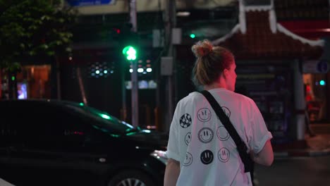 cautious female traveler walking across the busy streets of yaowarat road in bangkok chinatown