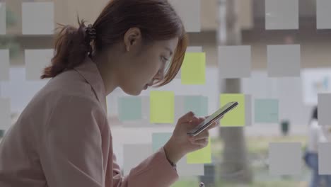 asian women use smartphones to do financial accounting work.