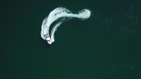 Aerial-bird-view-of-a-speedboat-riding-in-a-circle-and-making-beautiful-round-path-in-the-sea