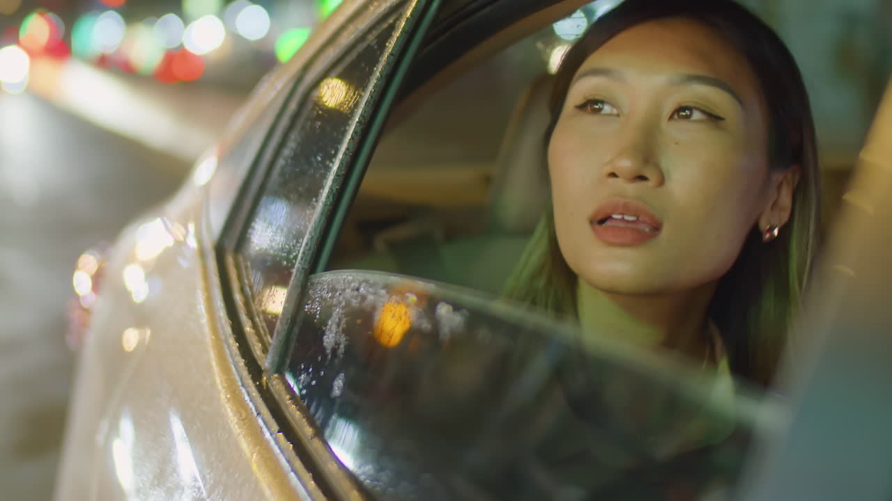 Asian Woman Taking Phone Call while Riding in Car at Night