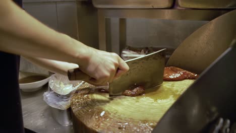 hombre cortando una rebanada de carne asada con un cuchillo de carnicero en guangzhou, china - de cerca